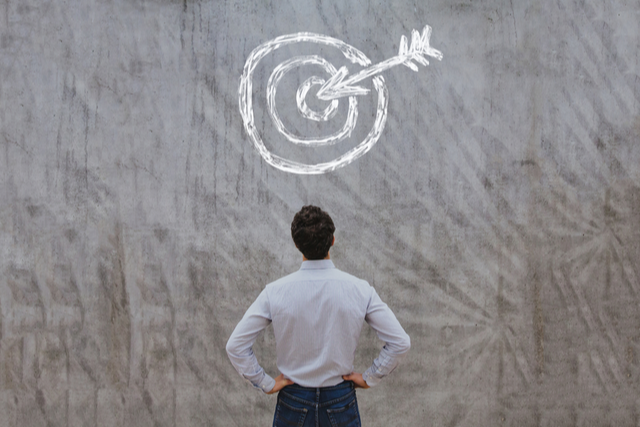 Man looking at a wall with handdrawn bull's eye